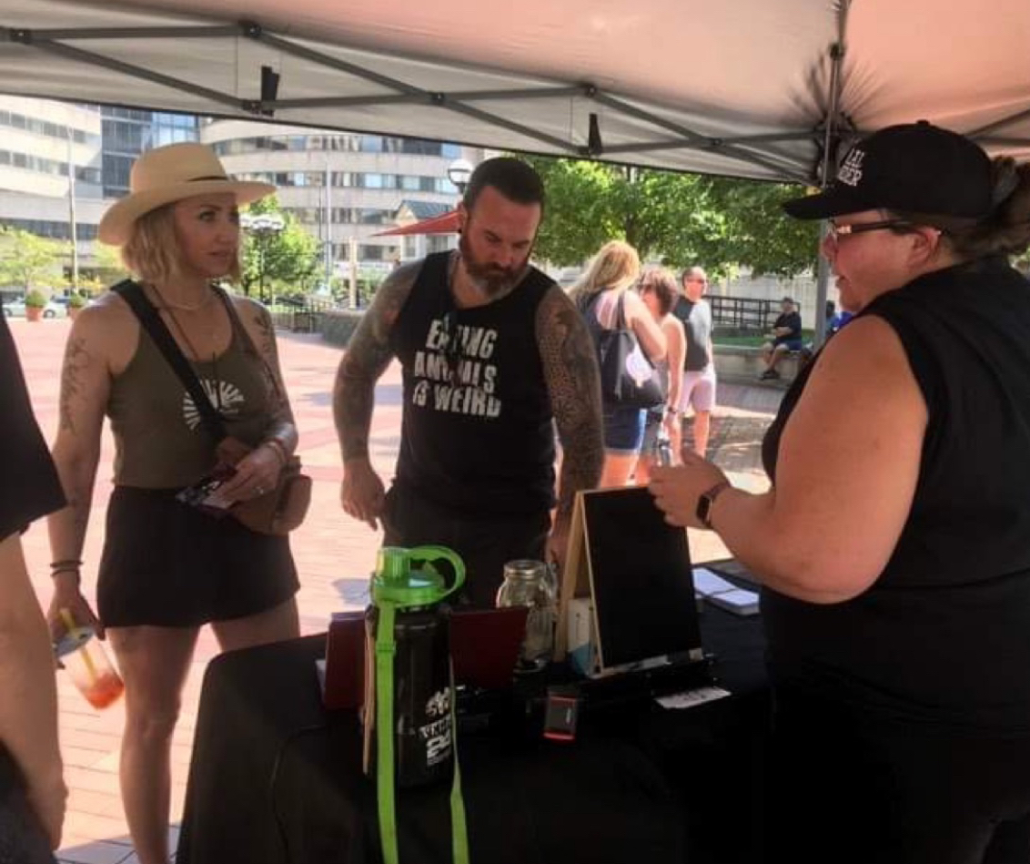 Two people at a table/booth hosted by another